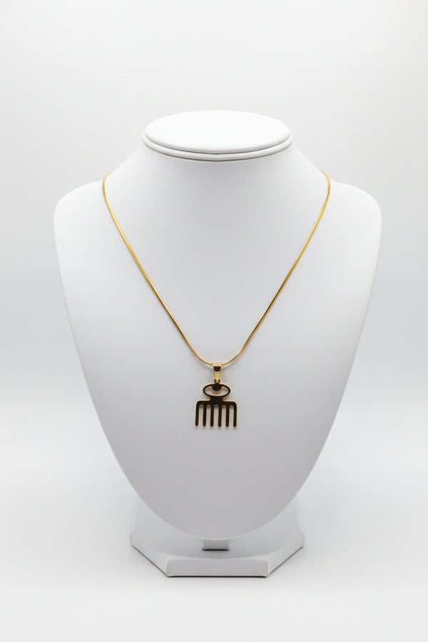 Gold-colored necklace with decorative end on a marble background