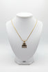 Gold-colored necklace with decorative end on a marble background