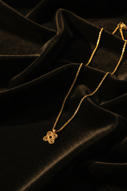 Gold necklace with a floral clasp on a marble surface