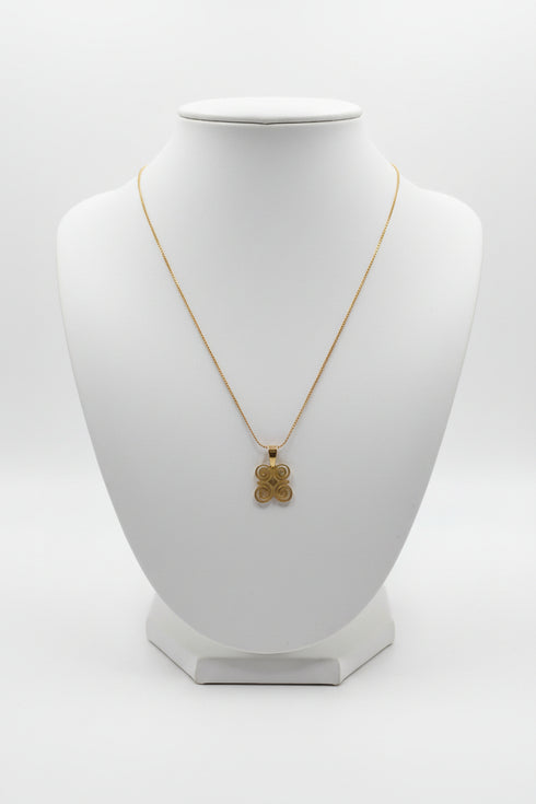 Gold necklace with a four-leaf clover pendant on a marble surface