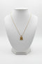 Gold necklace with a four-leaf clover pendant on a marble surface