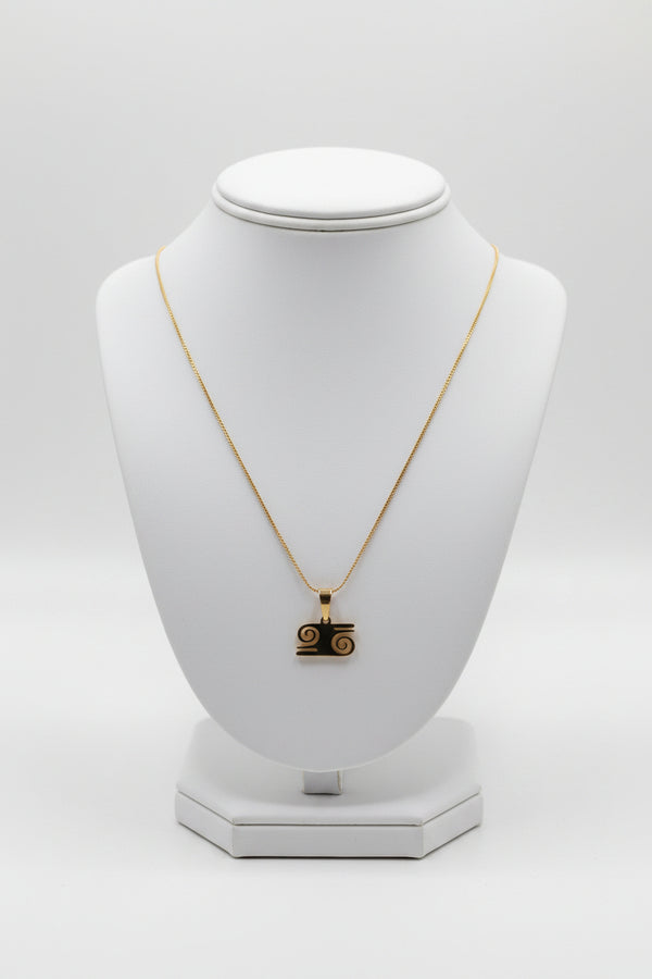 Gold necklace with a pendant on a white mannequin bust against a white background