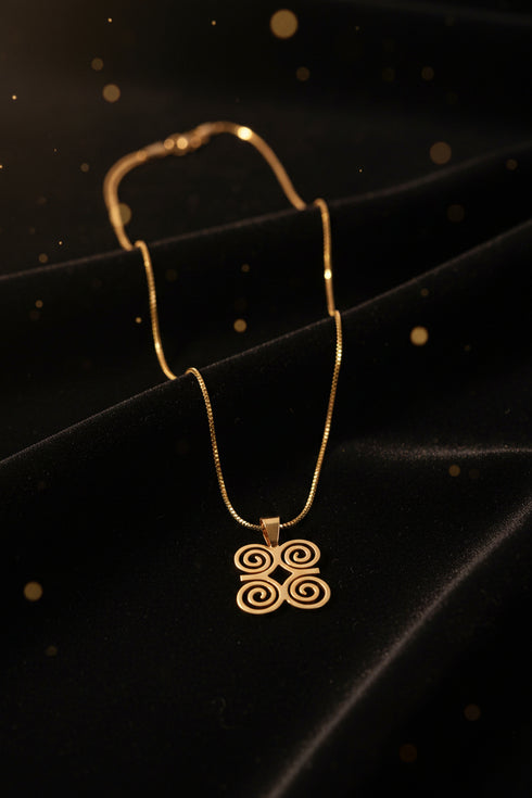 Gold necklace with decorative end on a marble background