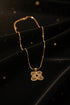 Gold necklace with decorative end on a marble background