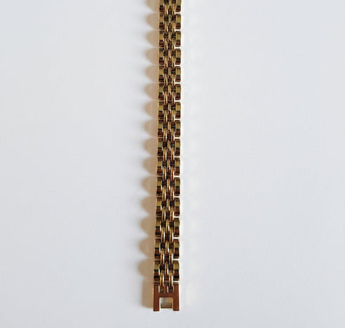 Gold bracelet with a green gemstone on a marble background