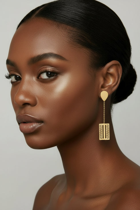 Gold earrings with black stones on a marble surface