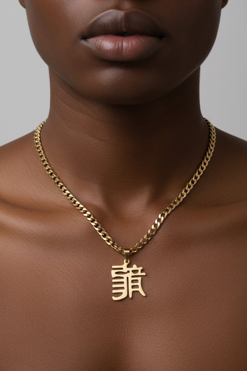 Gold chain necklace with a pendant on a marble surface