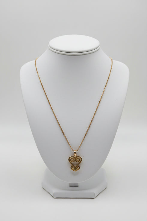 Gold necklace with a heart-shaped pendant on a white mannequin bust.