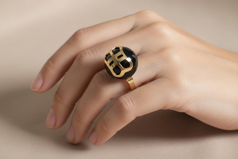 Gold ring with a black gemstone on a marble surface