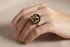 Gold ring with a black gemstone on a marble surface