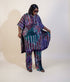 A woman models a matching two-piece printed outfit consisting of a loose short-sleeve top and wide-leg pants. The fabric features a complex pattern of purple, teal, pink, and white circular and floral motifs.