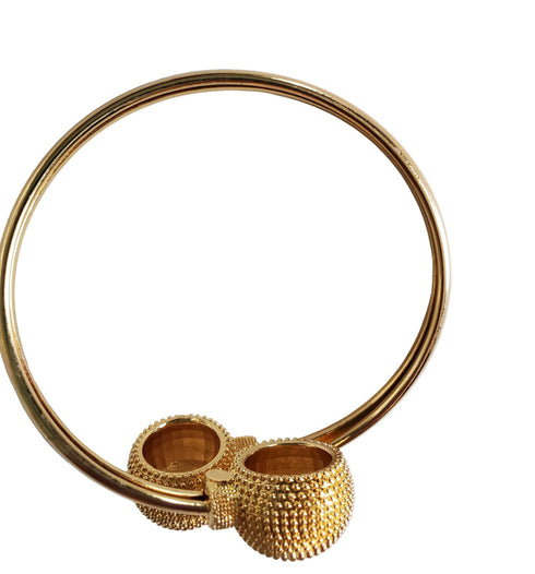 Gold bracelet with textured design on a marble surface