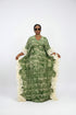 A woman modeling a green patterned kaftan dress with white ruffled trim, shown in a social media-style video frame with text overlays and phone interface elements.