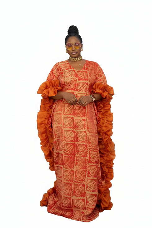 A woman modeling a vibrant orange and red patterned crepe maxi dress with a high waist, shown in a social media post with text overlays and a dark striped background.