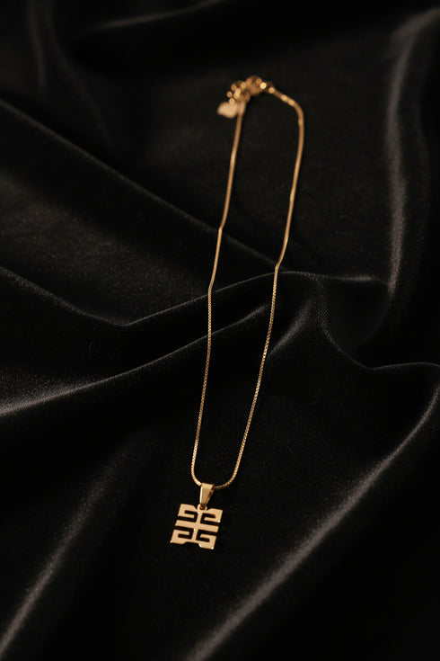 Gold necklace with a unique clasp on a marble surface