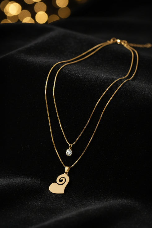Gold necklace with a heart-shaped pendant on a marble surface