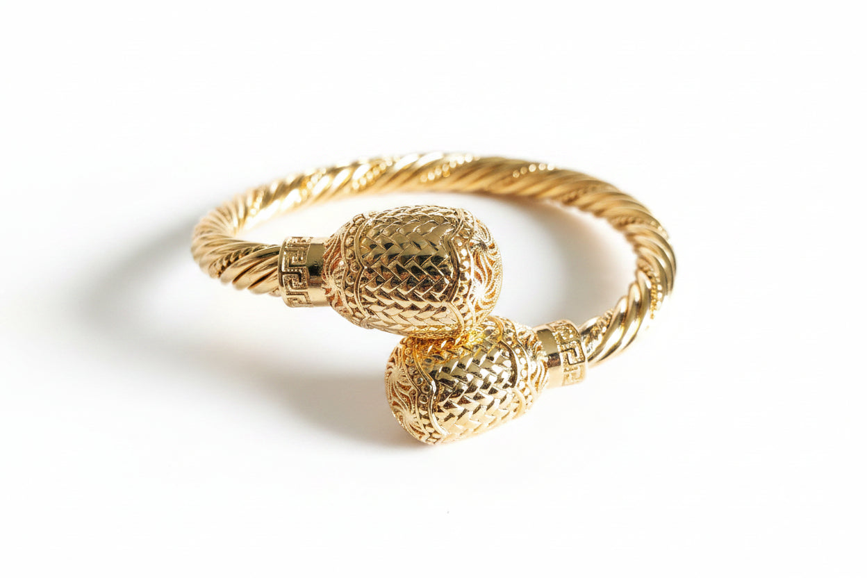 Gold bracelet with textured design on a white background