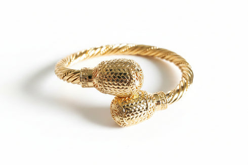 Gold bracelet with textured design on a white background