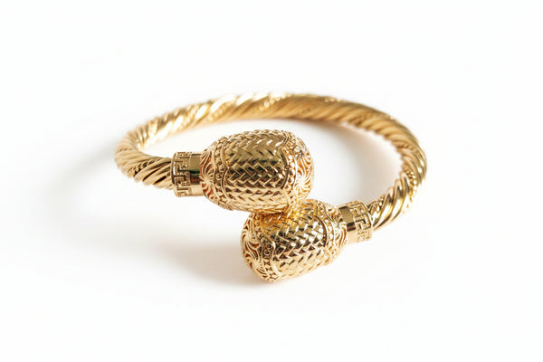 Gold bracelet with textured design on a white background