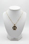 Gold necklace with a unique pendant on a marble surface