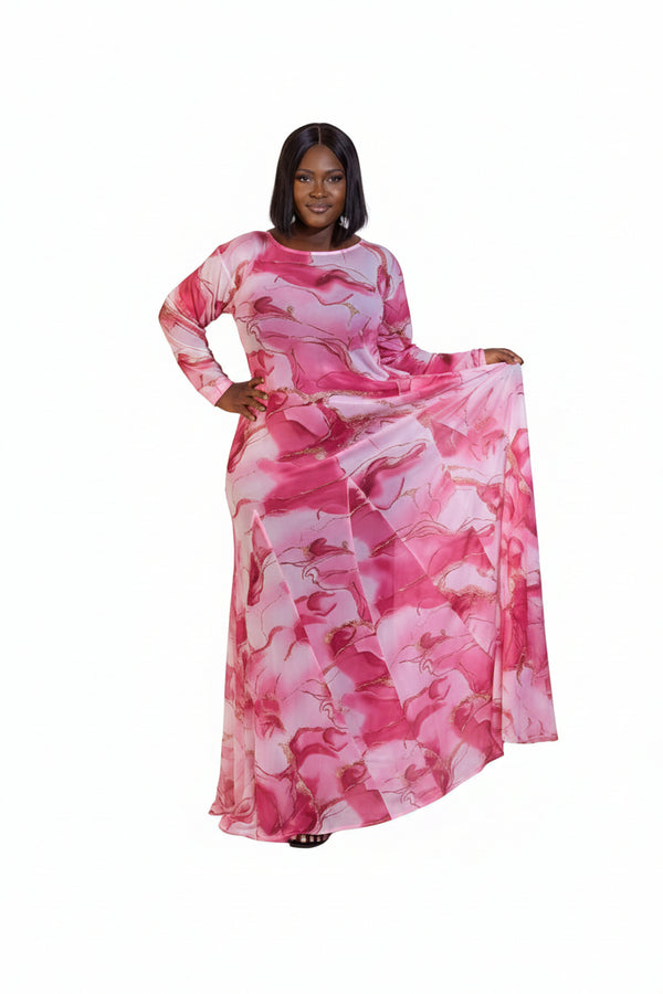 A woman modeling a long-sleeved maxi dress with a pink and white abstract watercolor pattern, standing against a plain white studio background.