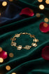 Gold bracelet with floral and circular designs on a marble surface