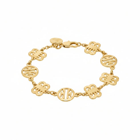 Gold bracelet with monogrammed charms on a marble surface