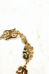 Gold bracelet with intricate design on a marble surface