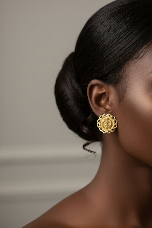 Close-up of a person wearing gold earrings with a neutral background