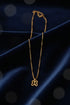 Gold necklace with a clover-shaped pendant on a marble surface