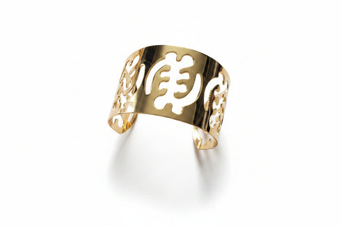 Gold bracelet with cut-out design on a marble surface