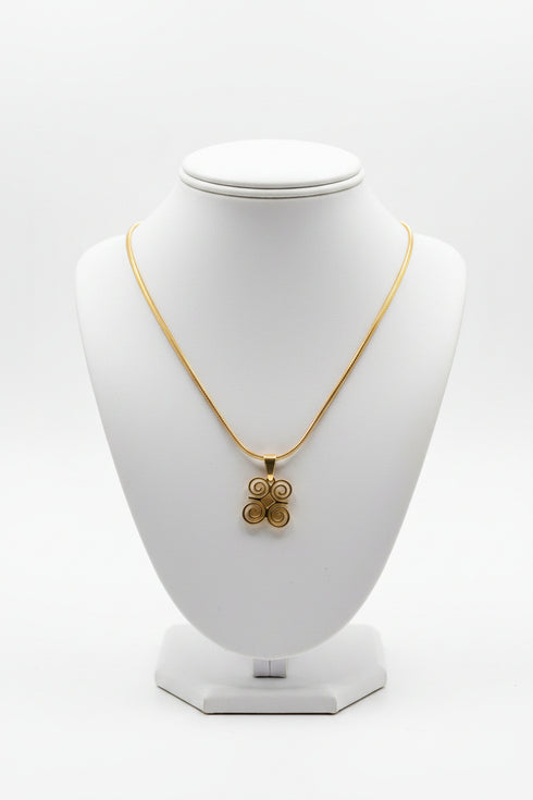 Gold necklace with a floral pendant on a marble surface