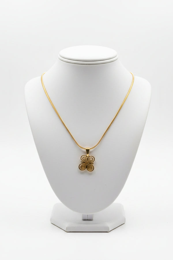 Gold necklace with a floral pendant on a marble surface