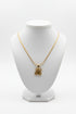 Gold necklace with a floral pendant on a marble surface
