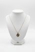 Gold necklace on a white mannequin bust against a white background