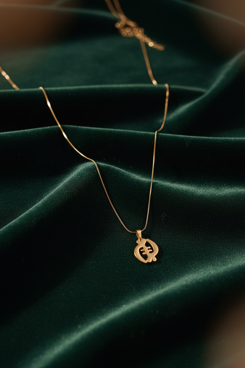Gold necklace with a pendant on a green fabric background