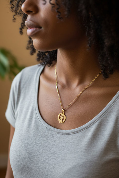 Gold necklace with a unique pendant on a marble surface