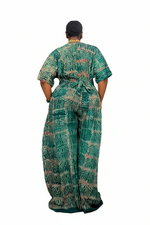 A person viewed from the back wearing a loose, short-sleeve matching set with an allover abstract wavy pattern in green, teal, and beige, photographed against a plain white background.