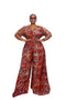 A woman modeling a red and gold patterned wide-leg jumpsuit with short sleeves and a V-neckline, standing against a plain white studio background.
