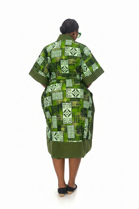 A woman viewed from behind wearing a green and white patterned kaftan robe with short wide sleeves, standing against a plain white background.