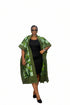 A woman modeling a green and black patterned open-front cardigan or kimono over a black dress, standing against a plain white background.