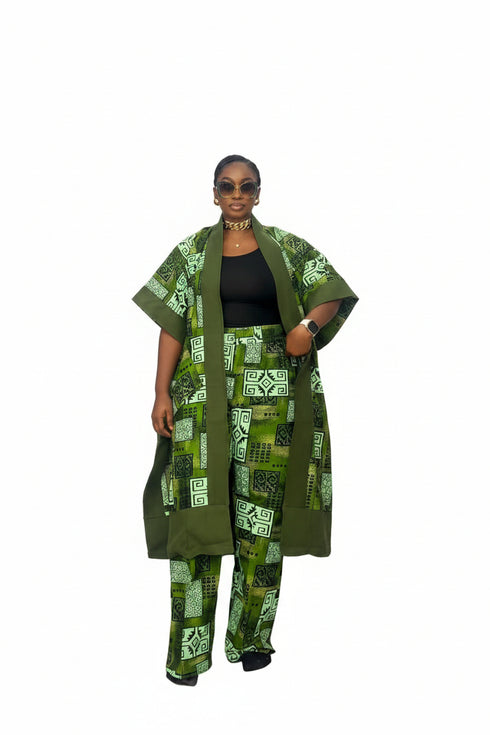 A woman modeling a matching green and black patterned two-piece outfit with a short-sleeve open-front jacket and wide-leg pants, photographed against a plain white background.