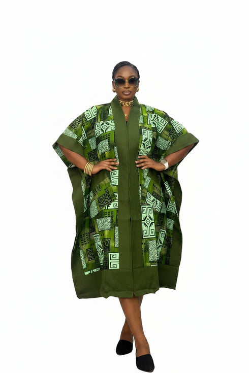 A woman modeling a green and white patterned kaftan dress with a solid green inner layer, photographed against a plain white background.